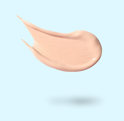 Skin foundation in air on light blue background. Cosmetic product