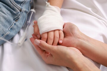 Doctor and child with IV drip in hospital, closeup