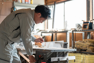 丸鋸・昇降盤を使う作業着姿の中年男性
