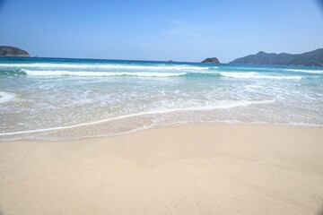 Fototapeta premium Serene Beach with Mountainous Backdrop and Clear Blue Sky, Sai Kung, Hong Kong
