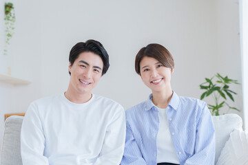 家のリビングで過ごす笑顔の30代夫婦
