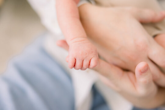 A baby is grasping onto his parents' hands