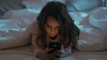 Gadget night. Kid insomnia. Late chat. Internet communication. Tired bored little girl using mobile...