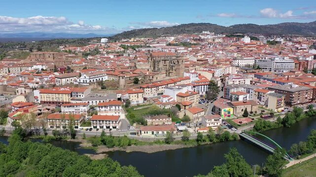 Picturesque aerial view of Plasencia city located in valley of Jerte river overlooking terracotta tiled roofs of residential buildings and medieval cathedral complex in spring, Extremadura, Spain