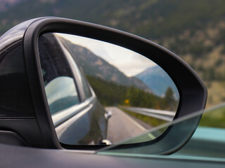 Fototapeta premium Driving on a road with mountains in the rearview mirror.
