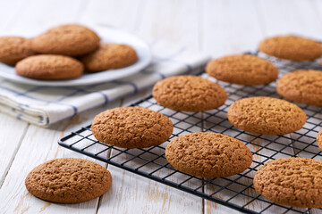 Oatmeal cookies are cooling after baking on a rack on a white table, selective focus.
