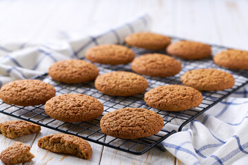 Freshly baked oatmeal cookies cooling on a black wire rack, with in a light kitchen table, selective focus.