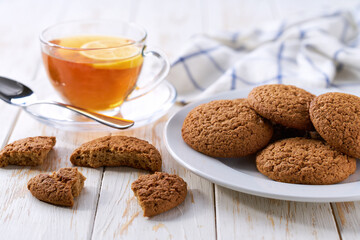 Oatmeal cookies and tea on a white table, close up.