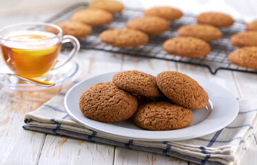 Low-calories oatmeal cookies and tea on a light kitchen table, selective focus.