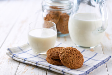 Tasty oatmeal cookies and glass milk on a light kitchen table, selective focus.