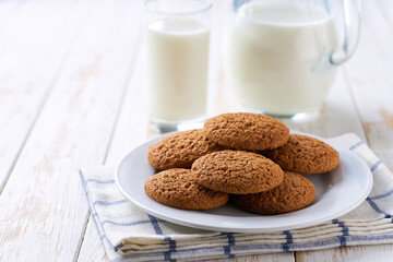 Low-calories oatmeal cookies and a jug of fresh milk on a light kitchen table,healthy breakfast.