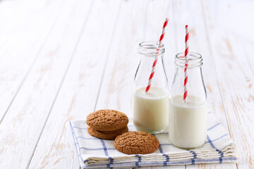 Tasty oatmeal cookies and bottles of fresh milk on a light kitchen table,healthy breakfast.