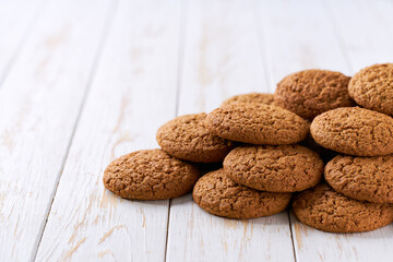 Heap of oatmeal cookies on a white table, with copy space for text.