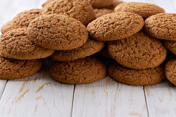 Heap of oatmeal cookies on a white table, selective focus.