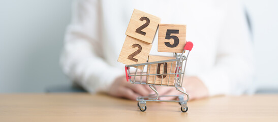 Happy new year with 2025 block in shopping trolley cart on table. E commerce, online shopping,...