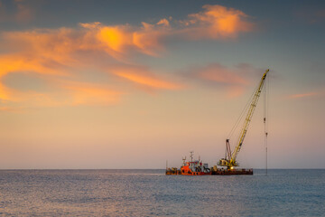 Fototapeta premium Floating crane on the sea at sunrise. Industrial landscape.