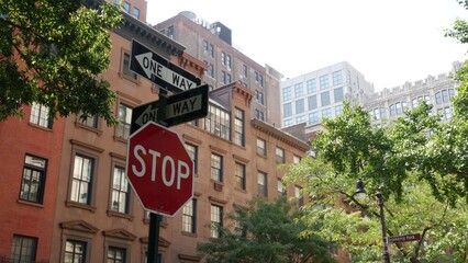 New York City oneway crossroad, Stuyvesant street intersection one way arrow. Manhattan Midtown residential building architecture, United States real estate. Red brick house wall, red stop road sign.
