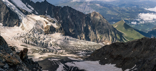 Dirty melted end of glacier under Mont Blanc between high rock walls and clouds