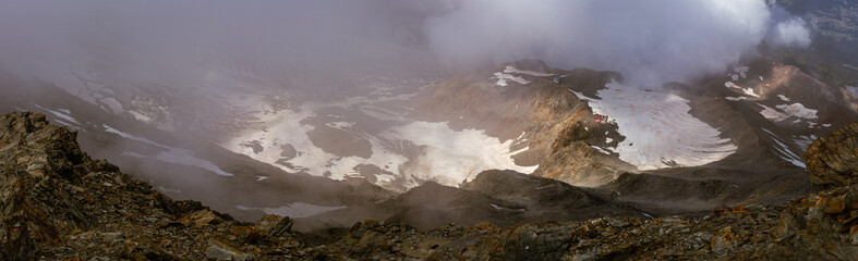 Tiny Tête Rousse Hut with glacier top view through clouds sun rays, france normal way Mont Blanc