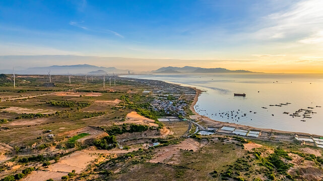 Tall windmill turbines against a clear blue sky, generating renewable energy in the serene Ninh Thuan, Vietnam landscape by the sea. Same with windmill park in the Noordoostpolder Netherlands