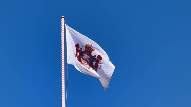 Waving Flag of Monaco against blue sky in sunlight. Close up slow motion shot. principality of Monaco,France.