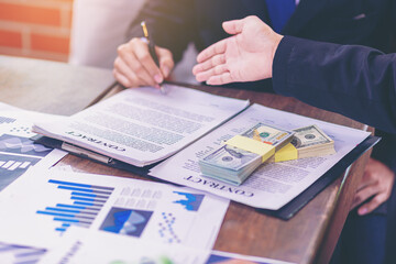 Businessman puts signature on contract at business meeting after negotiations with business partners. Selected focus