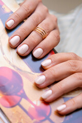 Client nails with fresh gel polish holding a magazine in a beauty salon. 