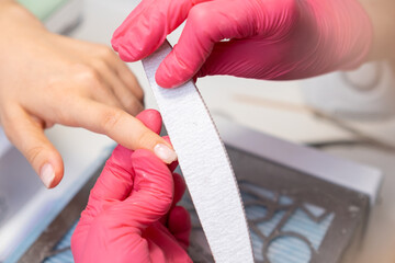 Professional manicure services with a nail file in a beauty salon. 