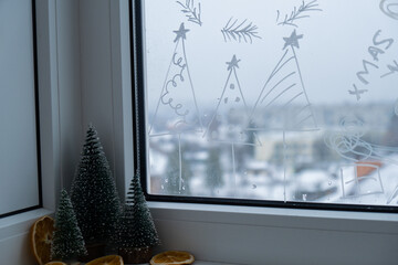 Painted window with white marker. Christmas tree decoration on big clear window. Snowy winter...