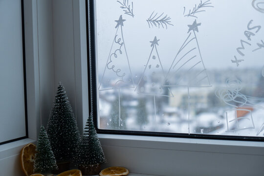 Painted window with white marker. Christmas tree decoration on big clear window. Snowy winter outside. Zero waste decor conscientious celebration. Holiday preparation