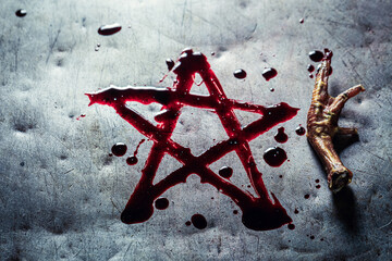 Pentagram drawn from blood with crow's paw on metal table