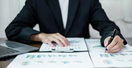 The businessman hand sits at their desks and calculates financial graphs showing the results of their investments planning the process of successful business growth