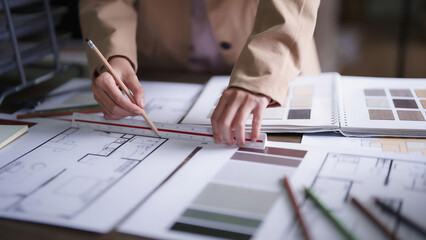 Female architect drawing building project and designing interior on blueprint with pencil and ruler
