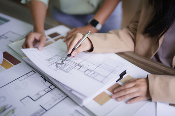 Two female architects discussing about interior designing building project and drawing on blueprint