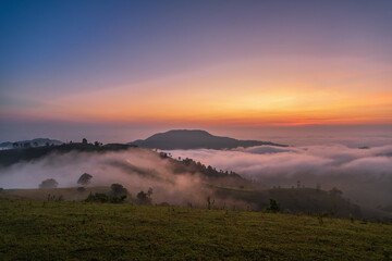 The sky is a beautiful orange color as the sun sets. The clouds are white and fluffy, creating a peaceful and serene atmosphere