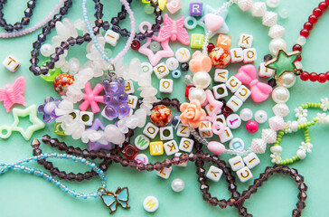 Colorful beads and charms scattered on a blue surface, showcasing various shapes and colors, ideal for crafting and DIY jewelry projects