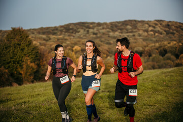 Runners are running a marathon in nature. They are wearing numbers on their sports clothes.