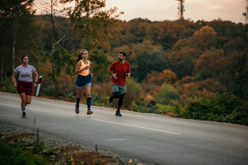 Obraz premium Three runners sprinting outdoors - Sportive people training in a nature area, healthy lifestyle and sport concepts