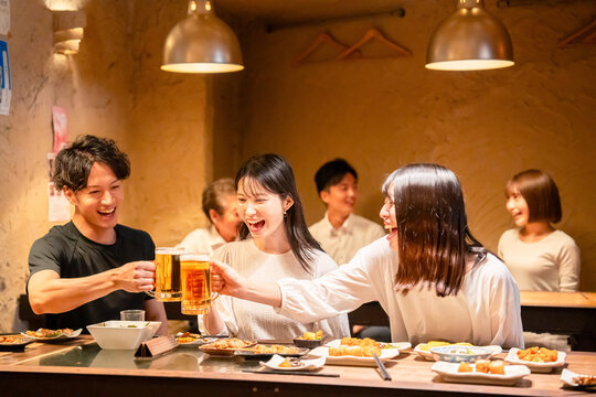 居酒屋でお酒を飲む若い男女