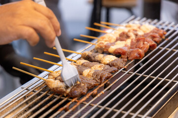 Thai style grilled BBQ beef on electric grilling mesh. Grilled beef skewers sticks.