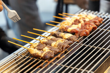 Thai style grilled BBQ beef on electric grilling mesh. Grilled beef skewers sticks.