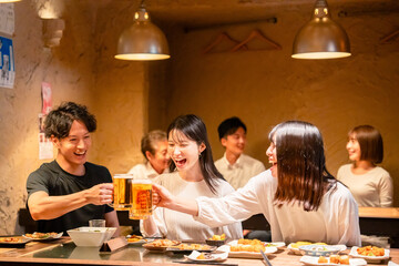 居酒屋でお酒を飲む若い男女