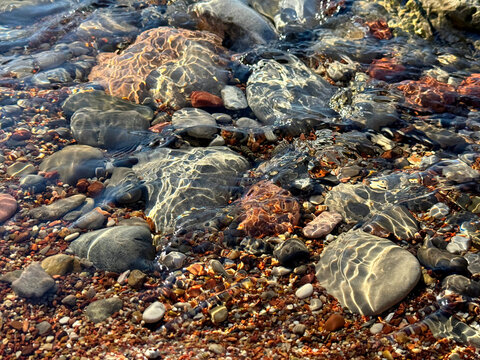 Smooth stones and pebbles in clear sea water on the beach.