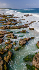 Vertical view of ocean rocks near a surfing beach.