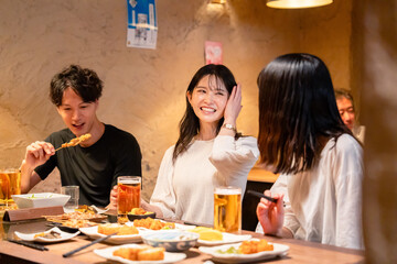 居酒屋でお酒を飲む若い男女