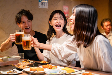 居酒屋でお酒を飲む若い男女