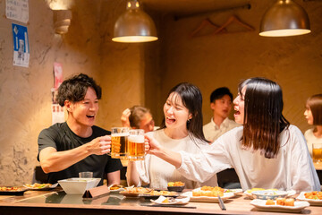 居酒屋でお酒を飲む若い男女