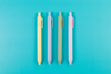 Top view of colorful pens on blue background. School, office wallpaper. Flat lay, copy space.