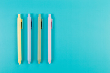 Top view of colorful pens on blue background. School, office wallpaper. Flat lay, copy space.