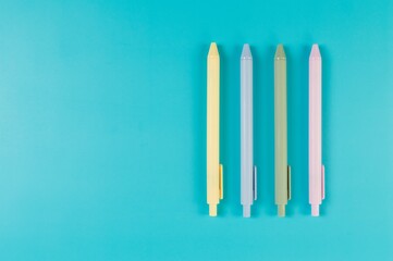 Top view of colorful pens on blue background. School, office wallpaper. Flat lay, copy space.
